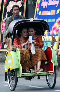 Tamu undangan melakukan selfie saat menaiki becak menuju tempat resepsi pernikahan Gibran- Selvi.