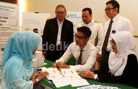 epala Group Pemasaran BPJS Kesehatan dr Budi M Arief, Kepala Kanwil Jakarta BPJS Ketenagakerjaan Rizani Usman, dan Senior Vice President Corporate Banking Bank Mandiri Arya Suprihadi menjelaskan manfaat BPJS kepada seorang nasabah yang sedang mendaftar di sela-sela sosialisasi.