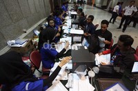 Warga duduk untuk menunggu giliran dipanggil ke meja pendaftaran.