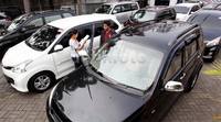 Petugas menjelaskan mobil-mobil bekas yang siap jual di diler mobil bekas mobil88, di Jalan Fatmawati, Jakarta Selatan, Senin (22/6/2015).