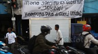 Para pengendara melintas di depan spanduk meminta ganti rugi dari warga Kampung Pulo.