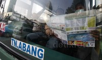 Seorang penumpang angkutan umum membaca peta mudik yang dibagikan para Polwan.     