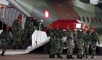 Para prajurit TNI menurunkan peti jenazah dari atas pesawat.