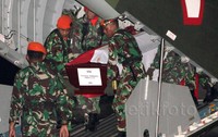 Para prajurit TNI menurunkan peti jenazah korban Hercules dari atas pesawat.