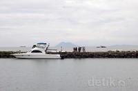 Para comic tengah melakukan adegan di tengah pantai dengan latar belakang panorama gunung yang indah.