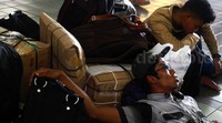 Beberapa calon penumpang menunggu kedatangan kereta dengan tiduran di lantai stasiun.