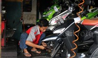 Seorang mekanik sedang memberikan perawatan kendaraan bermotor seorang pemudik.
