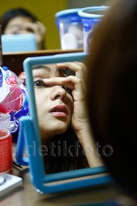 Ia tampak hati-hati saat memakai bulu mata palsunya.