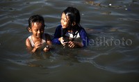 Dua anak kecil terlihat tersenyum senang saat berenang di pantai Ancol.