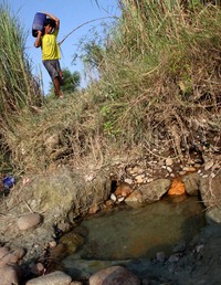 Warga berjalan kaki menyusuri sungai untuk mencari air bersih.
