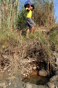 Seorang warga memanggul jerigen berisi air yang diambil dari sungai.