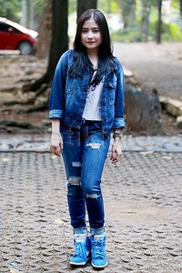 Prilly bergaya dengan kaus putih dipadu dengan jaket denim, jeans robek (ripped jeans) dan sneakers biru.