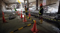 Beberapa pekerja merapikan tumpukan besi. Di bagian lainnya ada pekerja yang meratakan semen dari hasil pembetonan yang sudah selesai dilakukan.