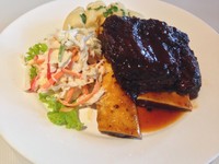 BBQ Beef Ribs berupa iga sapi Australia panggang lembut yang diberi bumbu khusus. Saus bbq kecokelatan tampak menggenang di bawah iga. Pelengkap sajian berupa coleslaw dan mashed potato.