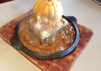 Apple Crumble Pie, apple pie bertopping es krim vanilla disajikan dalam hotplate. Ketika akan disantap, saus butterscotch kecokelatan berisi potongan apel disiram keatas apple pie.