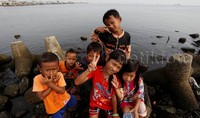 Sejumlah anak tampak asik berpose di atas batu pemecah ombak di pinggiran dermaga Muara Angke.