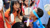 Para peserta berlomba-lomba menghabiskan kerupuk yang digantung di seutas tali.