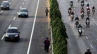 Penumpang berjalan di pinggir tol. Aksi tak tertib ini akan membahayakan diri sendiri dan pengendara yang melintas di tol tersebut.