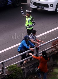 Tiga orang penumpang melompati pagar pembatas tol.