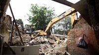 Backhoe berwarna oranye itu merobohkan rumah-rumah di pinggiran kali Ciliwung.