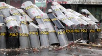Polisi bertahan di balik tameng.