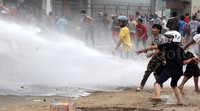 Polisi menembakkan water cannon ke arah warga.
