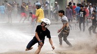 Warga membalas tembakan water cannon dengan lemparan batu.