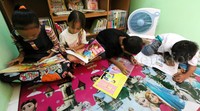 Anak-anak membaca buku di perpustakaan Pasar Manggis.
