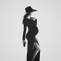 Cathy tampak sangat elegan dalam balutan dress gelap berlengan panjang dengan belahan kaki tinggi sepaha serta floppy hat. (Instagram/cathysharon)
