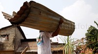 Seorang warga memanggul seng yang dikumpulkannya di lokasi penggusuran.