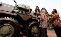 Seorang pengunjung wanita, menaiki kendaraan Panser Anoa 2 produksi PT Pindad, yang dipamerkan.
