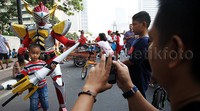 Seorang anak foto bersama robot dan senjatanya.