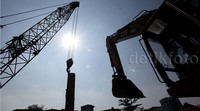 Alat berat menancapkan tiang-tiang pancang turap.