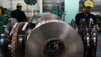 Dua orang pekerja menyelesaikan pembuatan stainless steel strip.