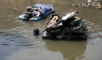 Para warga berenang sekaligus mendorong sampan yang berisikan tumpukan sisa-sisa barang bongkaran bangunan.