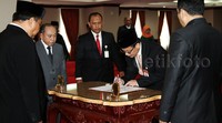 Guntur Hamzah menandatangani berita acara pelantikan.