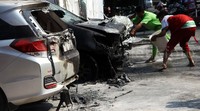 Dua orang petugas SPBU menyiram mobil itu dengan air.
