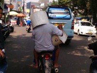     Karena terlalu banyak bawaannya, penumpang sampai harus menutupi kepalanya dengan ember. (Foto Farux, untuk Street Shot)