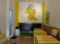 Dengan warna kuning dengan jajaran kursi kayu membuat tempat ini terasa hangat. DI bagian dindingnya juga terdapat lukisan lucu berbentuk es krim.