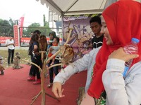 Seorang remaja mencoba bercengkerama dengan burung hantu yang hinggap di tangannya.