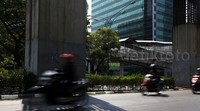 Pengendara melintas di antara tiang-tiang monorel di Jalan HR Rasuna Said.