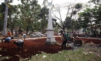 Pekerja meratakan tanah yang akan ditumbuhi rumput.