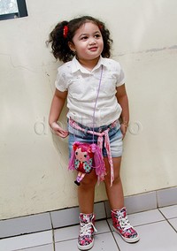 Amora tampil cute dibalut baju putih, hot pants denim, sepatu bunga-bunga, dan tas boneka Lalaloopsy. Pool/Gus Mun/detikFoto.