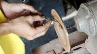 Seorang pekerja menghaluskan frame kacamata menggunakan mesin.
