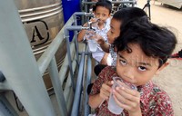 Seorang anak minum dari alat penyulingan air.