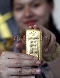 Seorang costumer service menunjukan emas batangan di butik emas, Gedung Antam, Jakarta, Jumat (18/9/2015).
