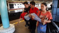 Petugas membopong korban benturan dua kereta.