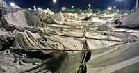 Kain terpal putih besar terhampar menutupi karpet merah yang menjadi alas tenda.