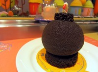 Cake berwarna cokelat ini mirip seperti bomb. Diisi dengan mousse hazelnut yang lembut dengan sponge cake cokelat dan diisi dengan bola-bola cokelat mungil. Rasanya manis!