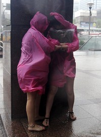 Dua orang warga berlindung di balik tiang gedung. Pichi Chuang/Reuters/detikFoto.